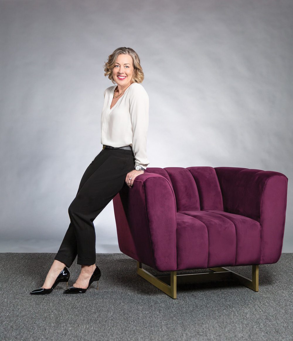 Sue sitting on the arm of a red chair